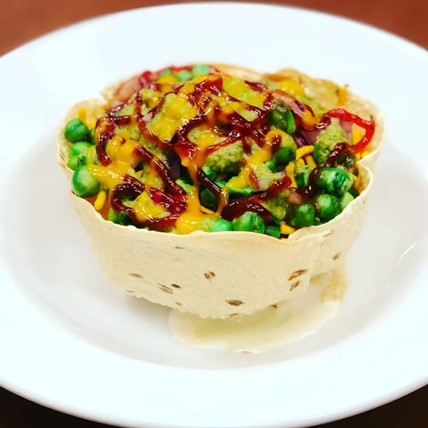 Namaste Kitchen's Indian chaat, a crispy papadum bowl filled with green peas and colorful sauces.