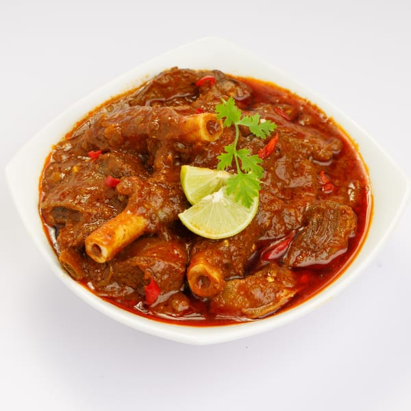 Namaste Kitchen's Indian lamb curry with bone-in meat, garnished with lime and cilantro.